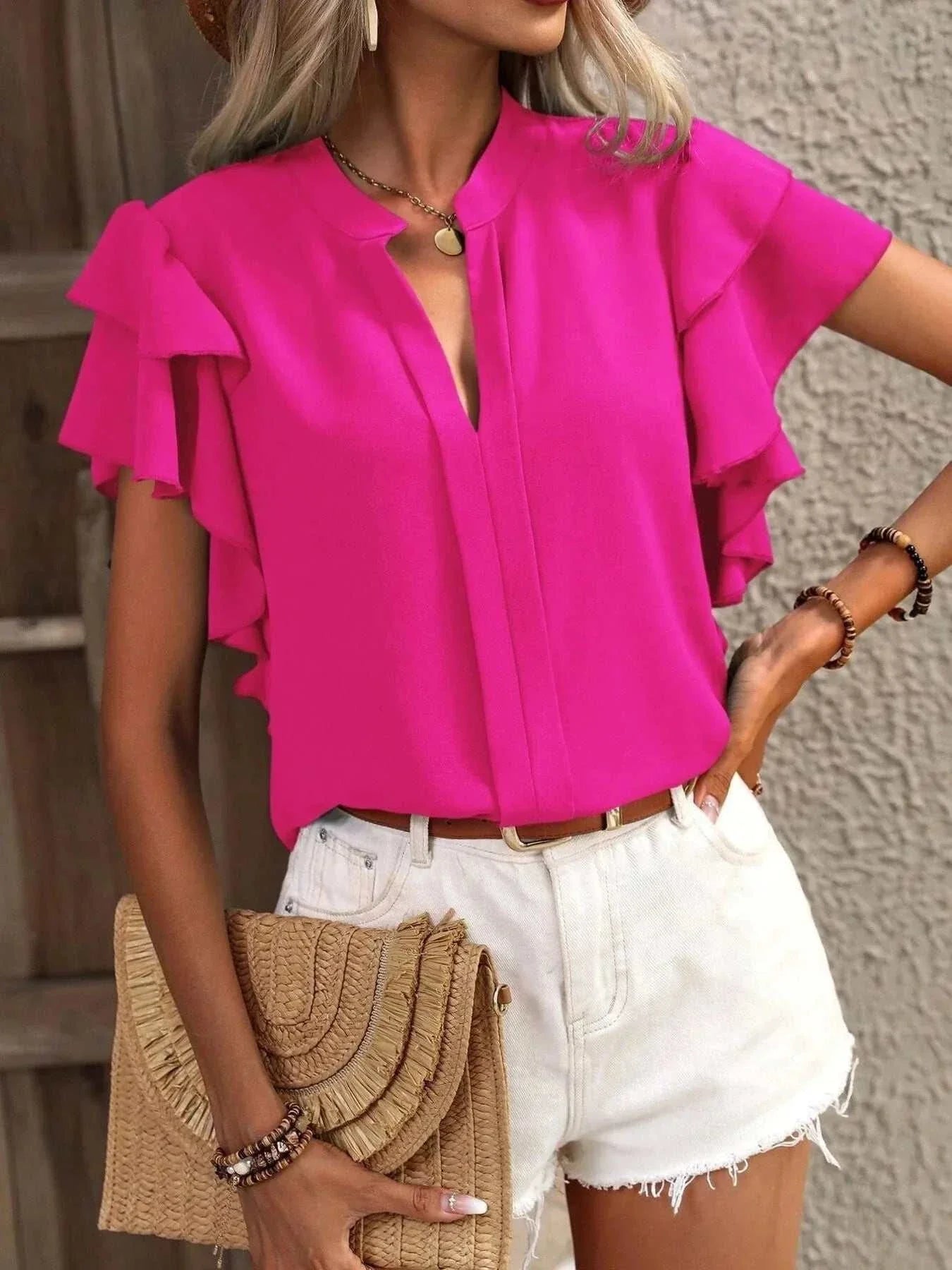 Bright pink ruffle sleeve notched blouse made of 100% polyester paired with white shorts and accessories.