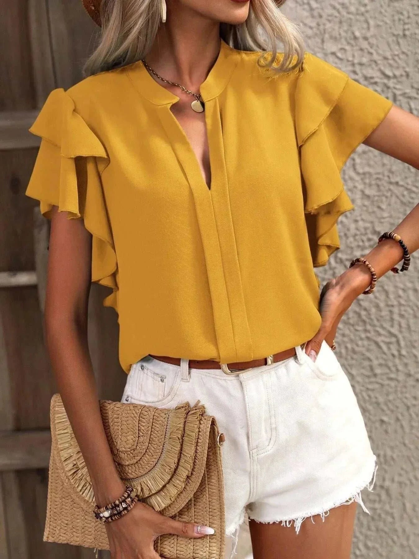 Yellow ruffle sleeve notched blouse with no stretch made of 100% polyester paired with white shorts.