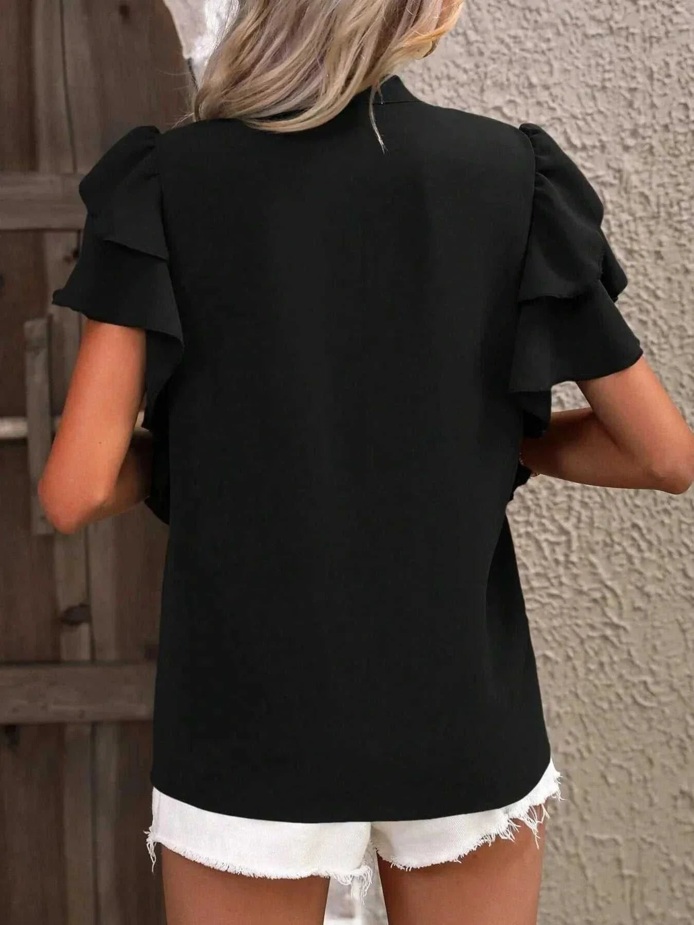 Black ruffle sleeve notched blouse made of 100% polyester with no stretch, styled with white shorts.