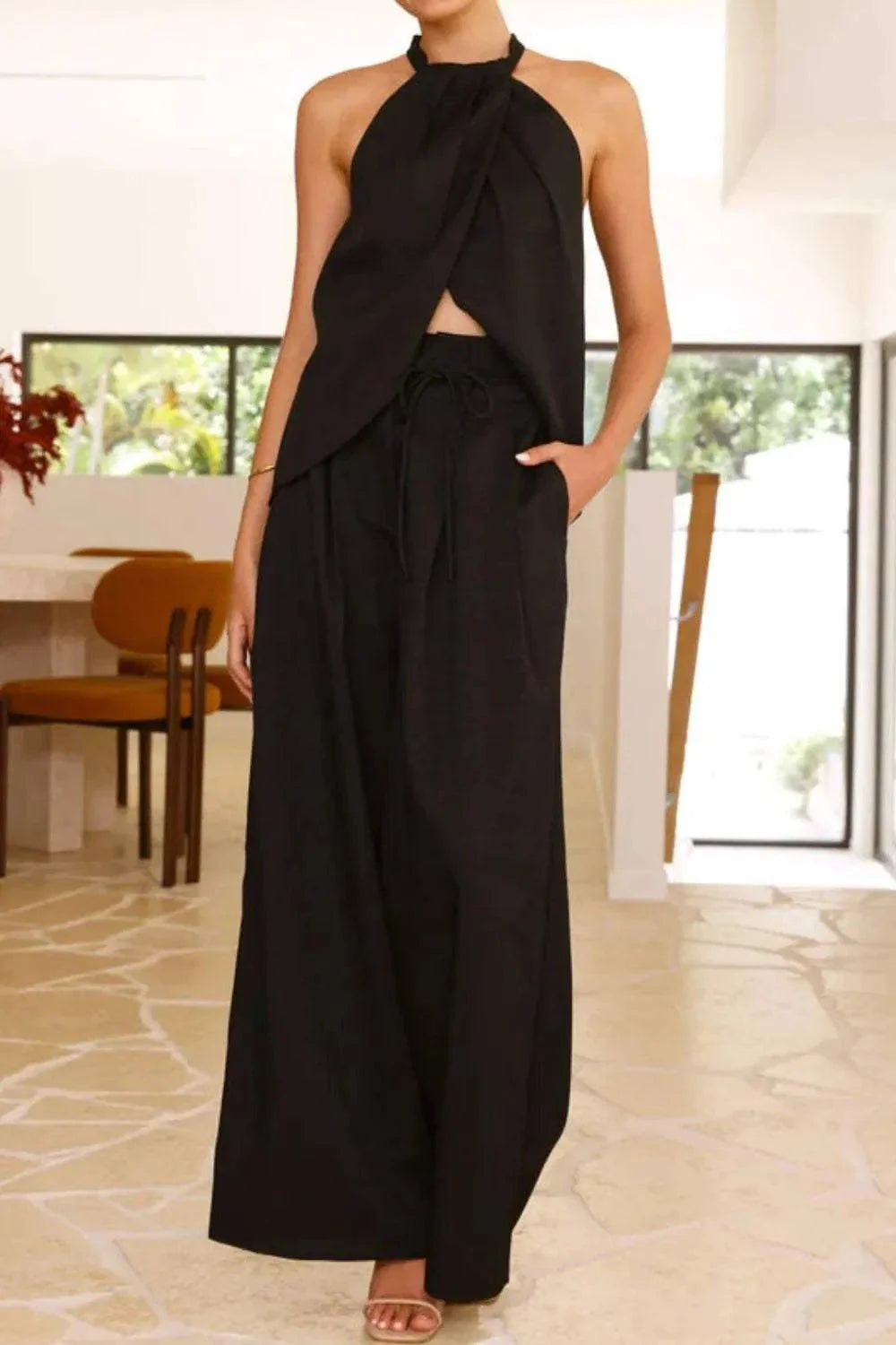 Black halter neck top and wide leg pants two-piece set with tied detail and pockets.