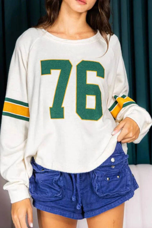 White Number 76 round neck long sleeve top with green and yellow stripes on sleeves, paired with blue shorts