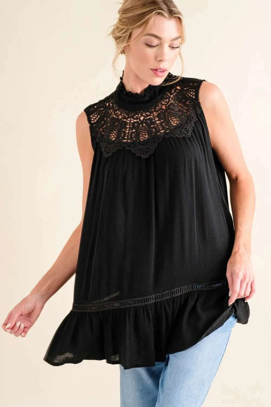 Woman wearing black lace detail sleeveless ruffled top with high neck and casual jeans