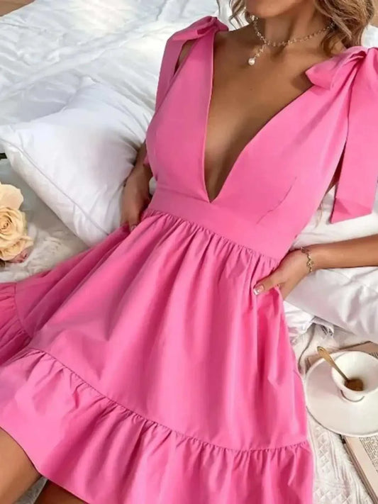 Pink tie shoulder tiered mini dress with deep V-neck and bow details