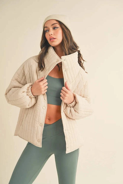 Kimberly C Classic beige quilted snap down jacket with high neckline and body-skimming fit worn by model
