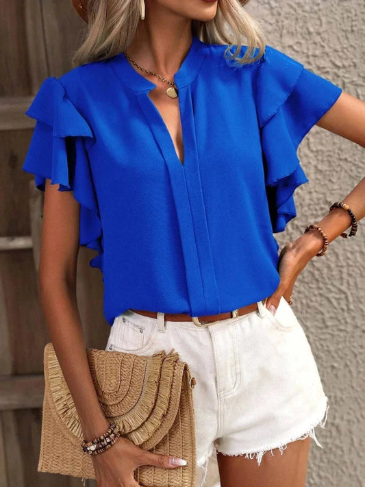 Blue ruffle sleeve notched blouse made of 100% polyester with short sleeves, styled with white shorts and a woven clutch.