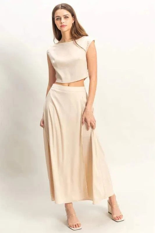 Woman wearing beige sleeveless top and maxi skirt set with a flowy silhouette.